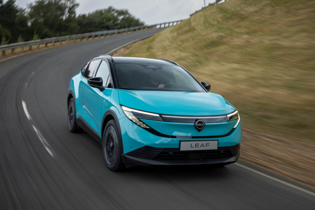 Une Nissan Leaf roule sur un route goudronnée, dans un virage.